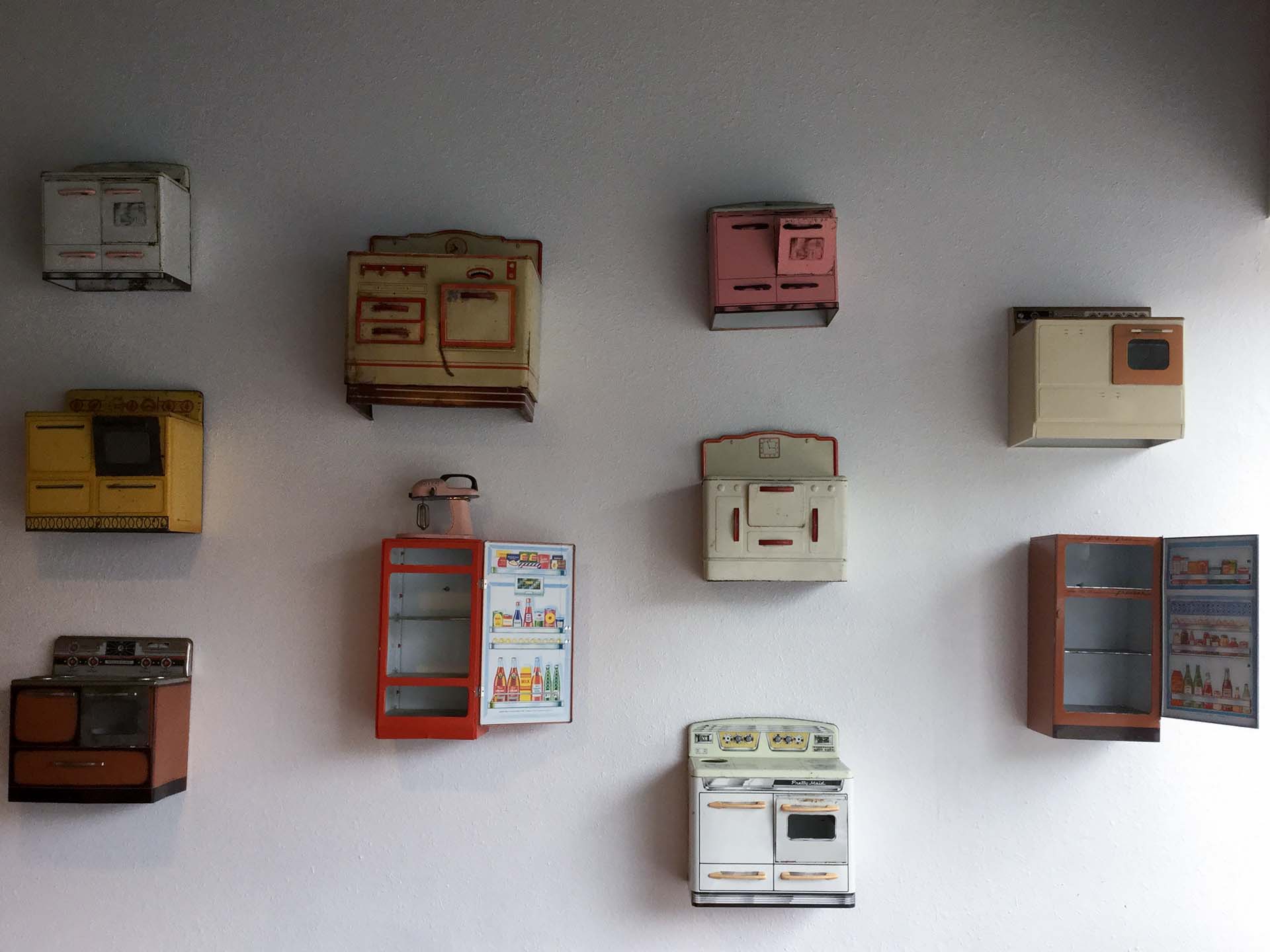 Metal toy appliances mounted on a white wall