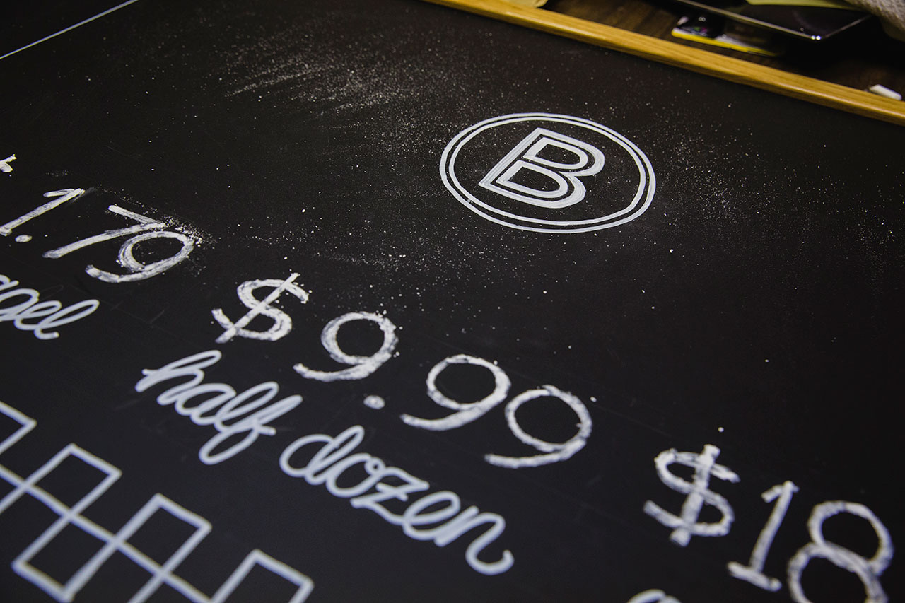 Close-up of chalkboard displaying BernBaum's B icon and pricing for bagels