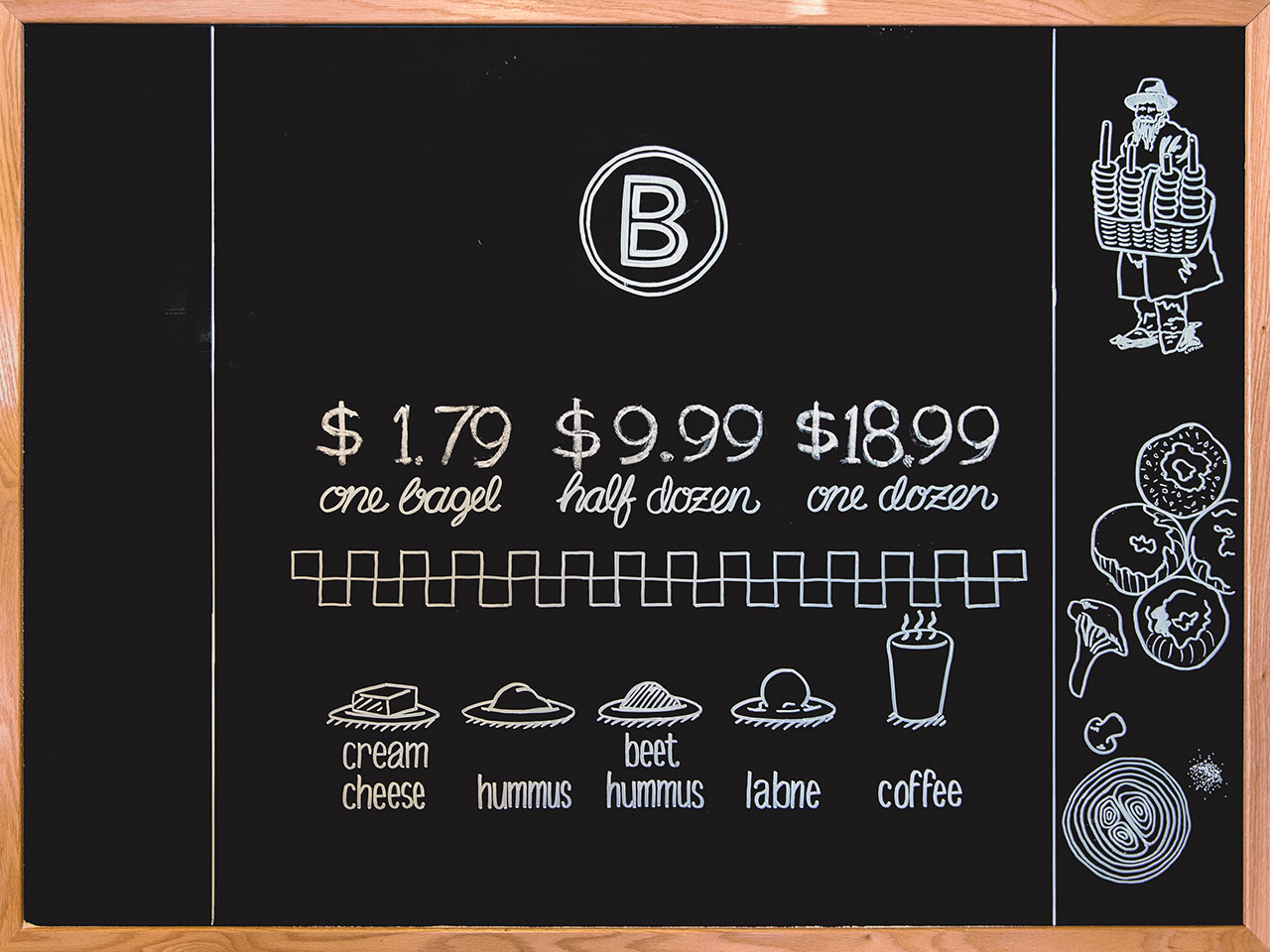 Black chalkboard with white chalked BernBaum's B logo, pricing for bagels, and illustrations of spread options
