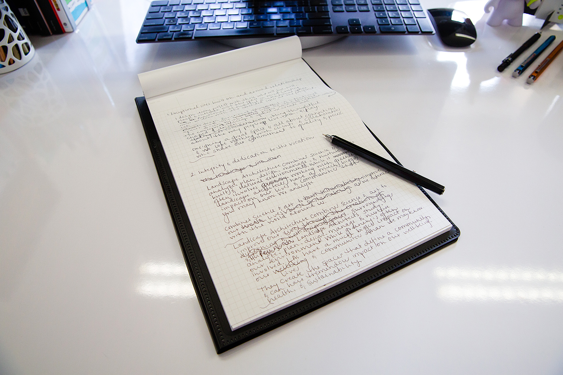 Pen and notepad displaying written content for website copy on white desk