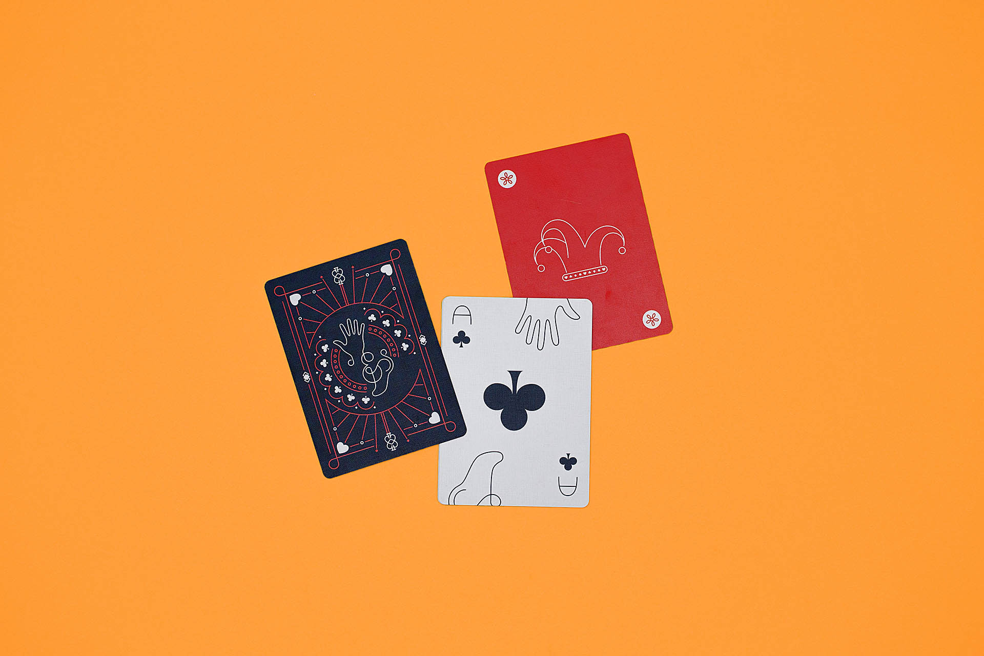 A dark gray card, ace of clubs face-up, and red joker face-up on an orange background