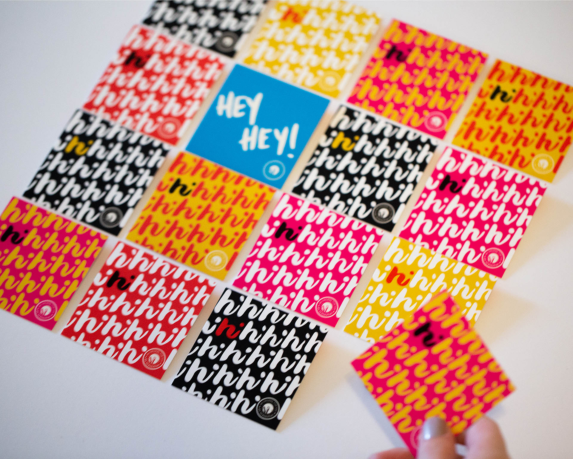 A hand grabbing the corner card out of a grid of colorful square cards