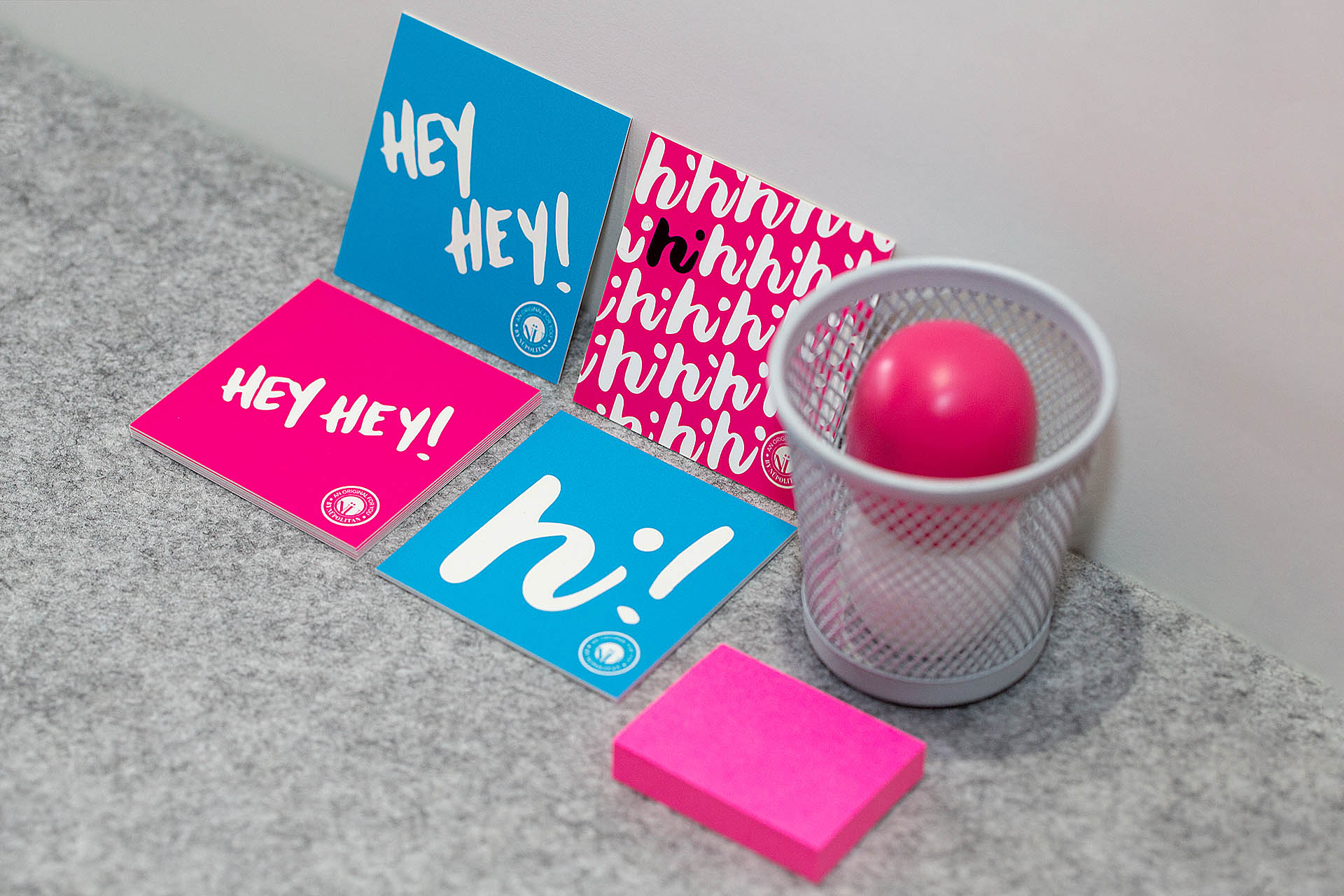 Two blue and two pink cards, a gray pencil cup, and pink post-it notes on gray felt