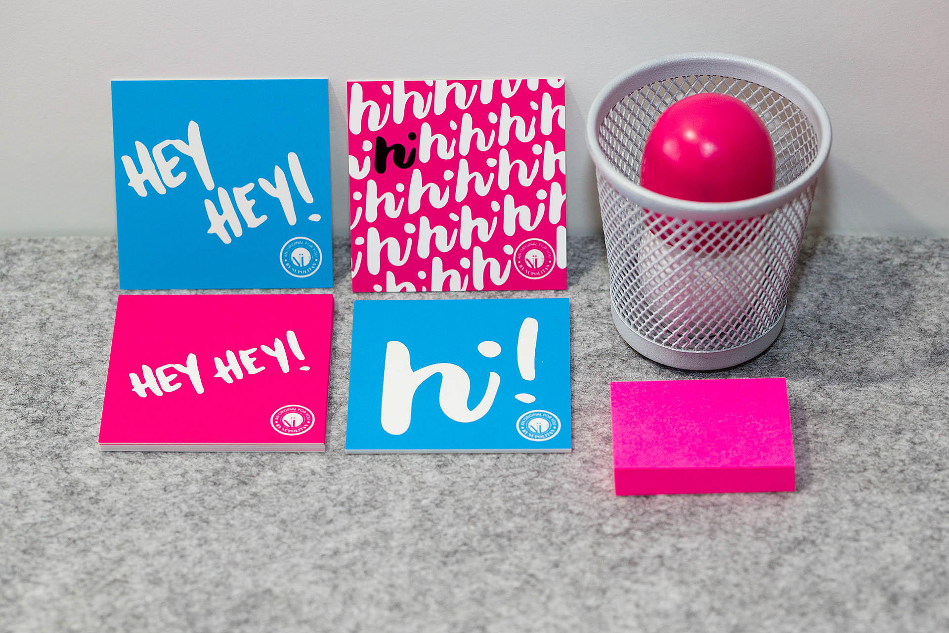 Two blue and two pink cards, a gray pencil cup, and pink post-it notes on gray felt