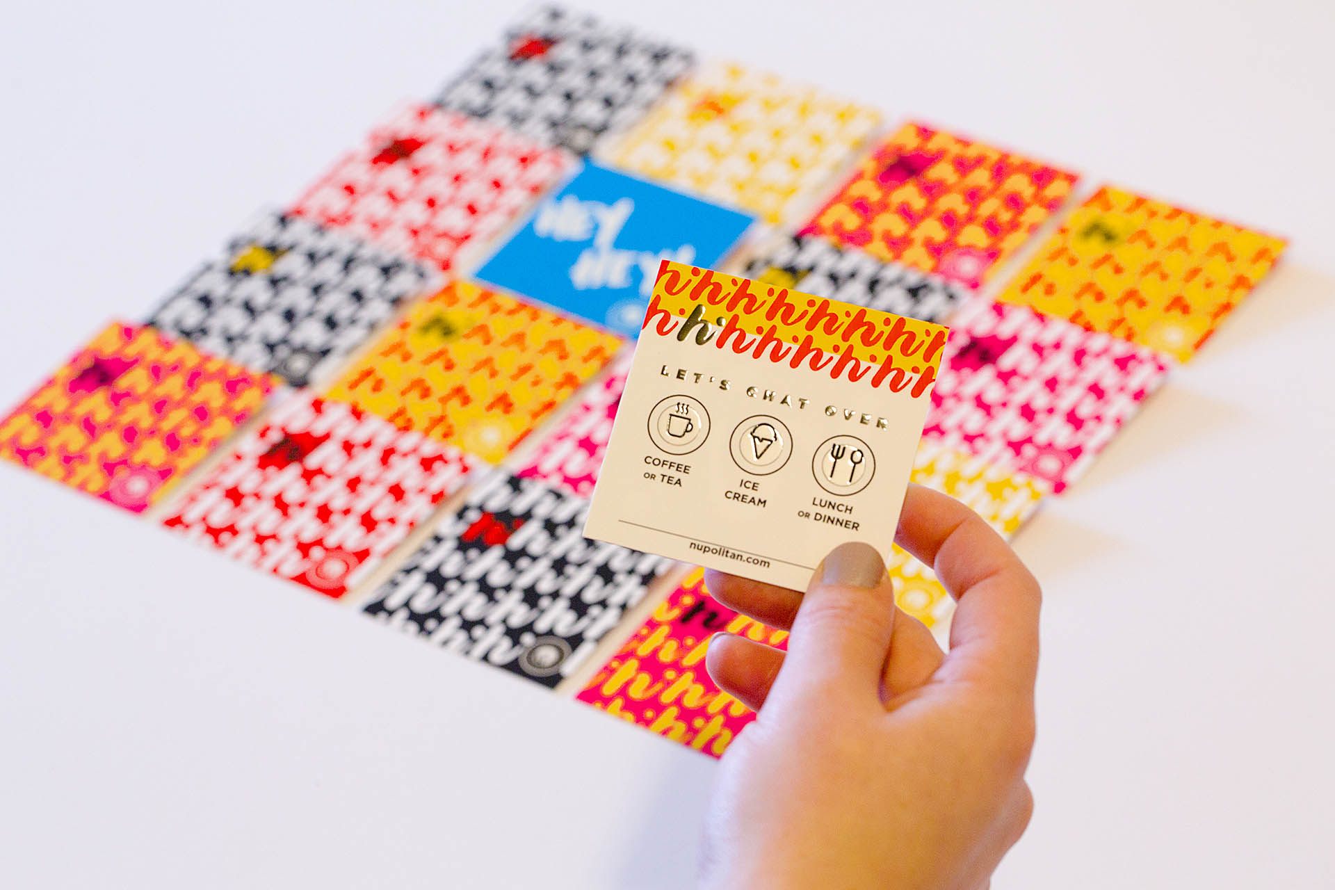 A hand holding a card over a blurred grid of colored, square cards in the background