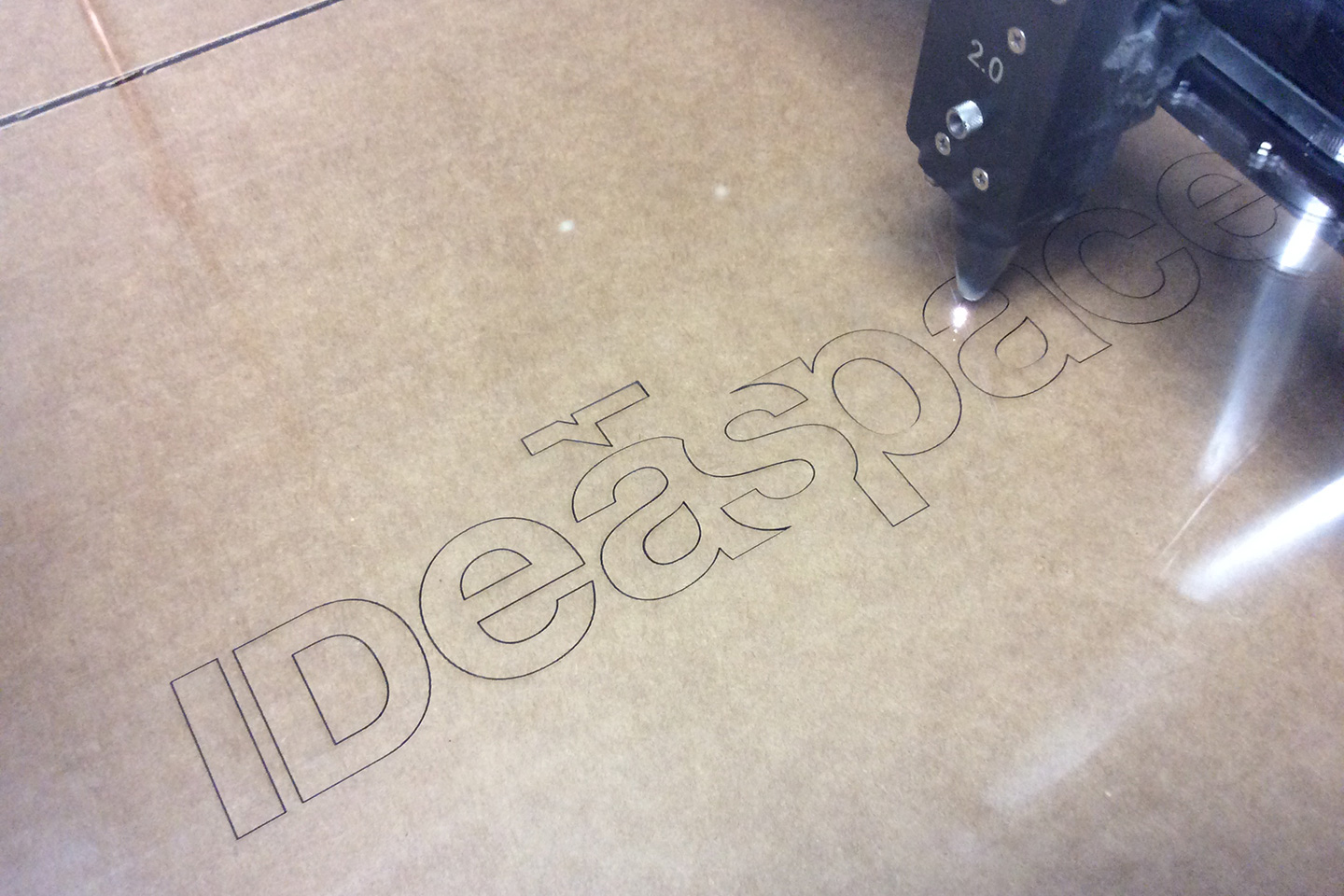 Laser cutter cutting the IDeaspace logotype out of clear acrylic
