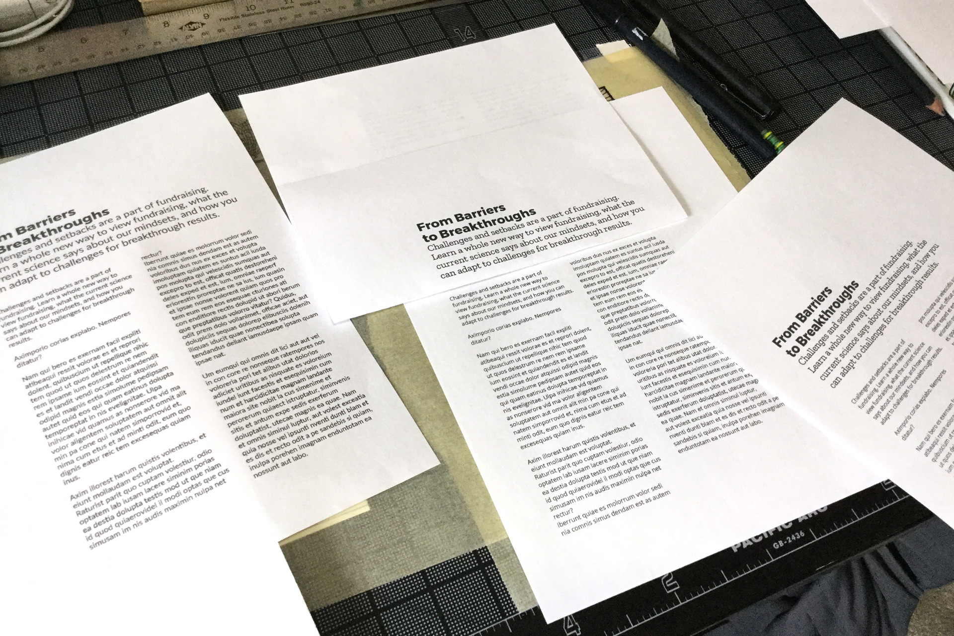 Pieces of white paper with typography samples on a black desk