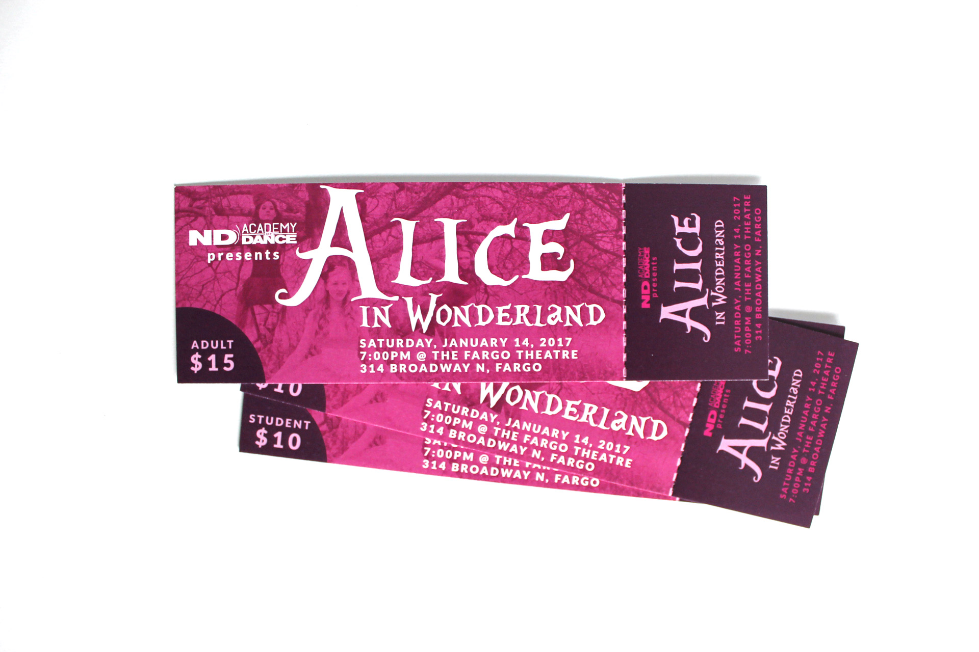 Stack of pink and purple tickets to Alice in Wonderland on a white backdrop
