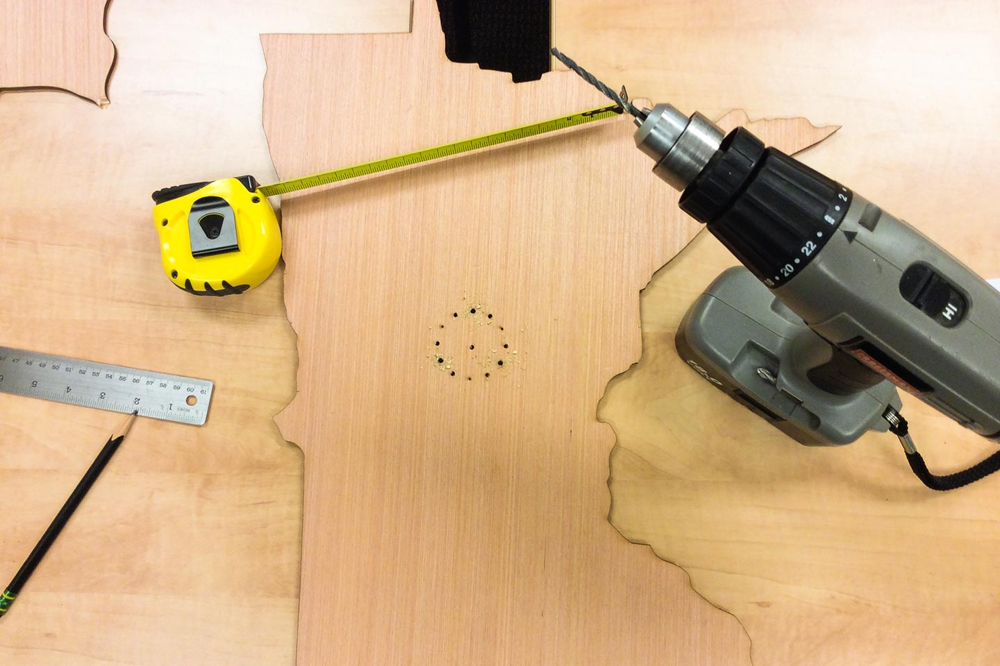 Drill, tape measure, and wood in the shape of Minnesota