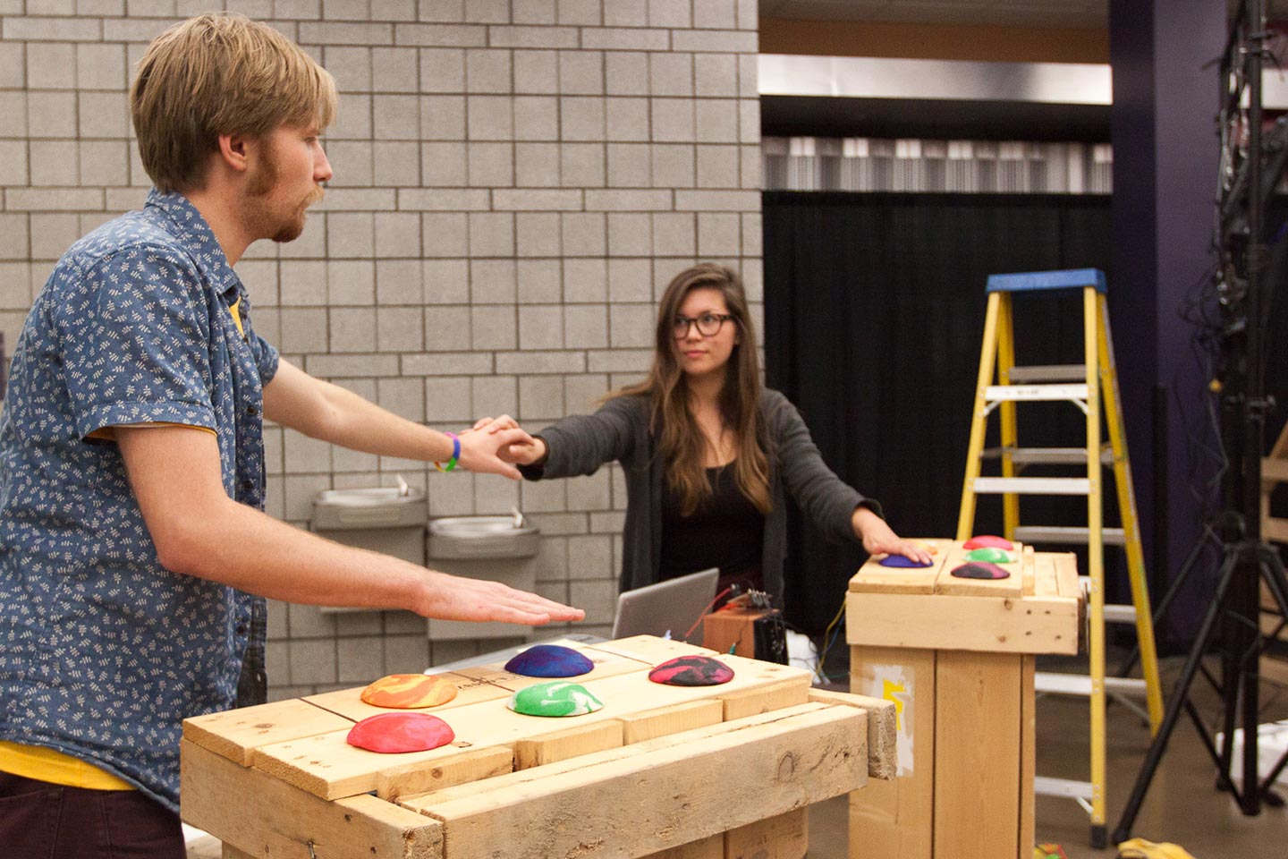 Man and woman holding hands while interacting with makey makey clay installation