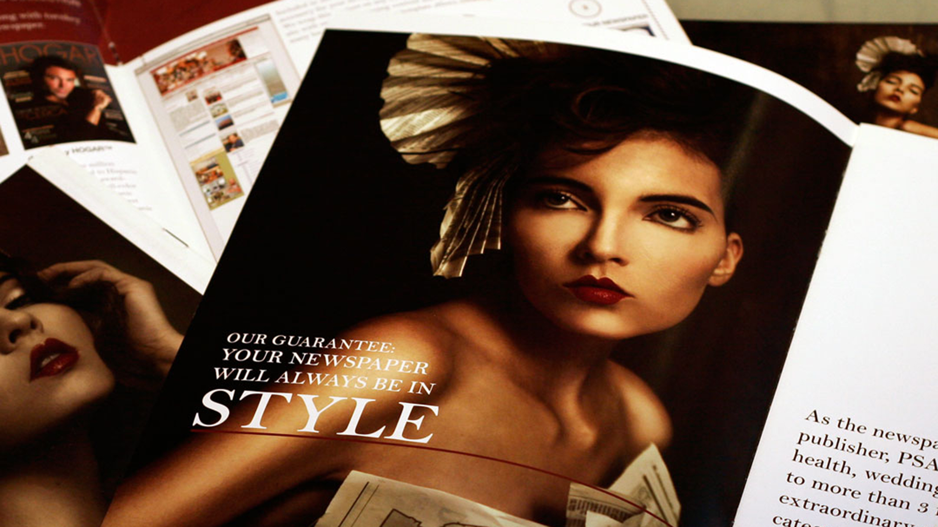 Magazine open to photo of woman wearing newspaper dress and hat on top of other open magazines