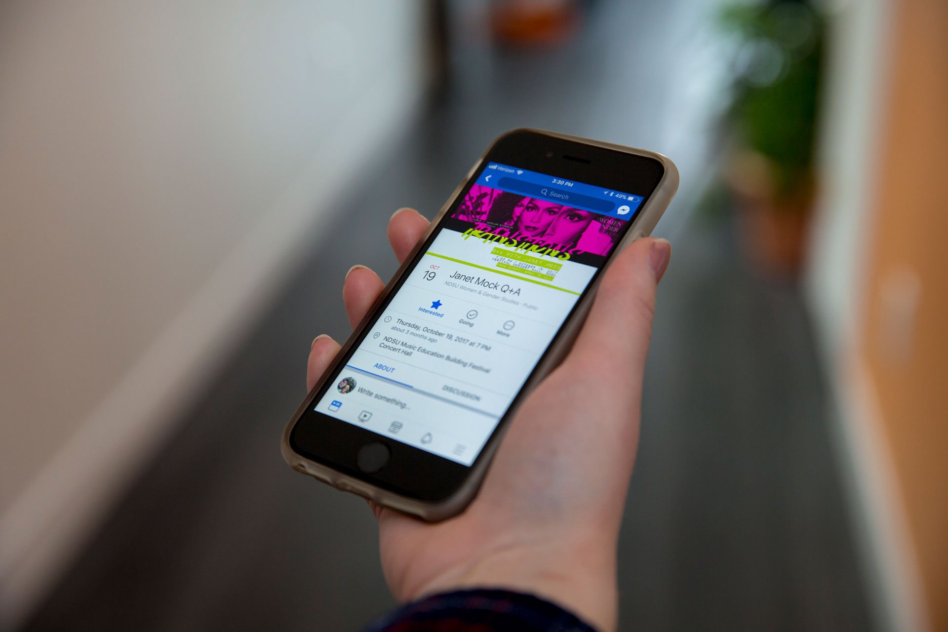 A hand holding an iPhone displaying a Facebook event with pink and green cover photo